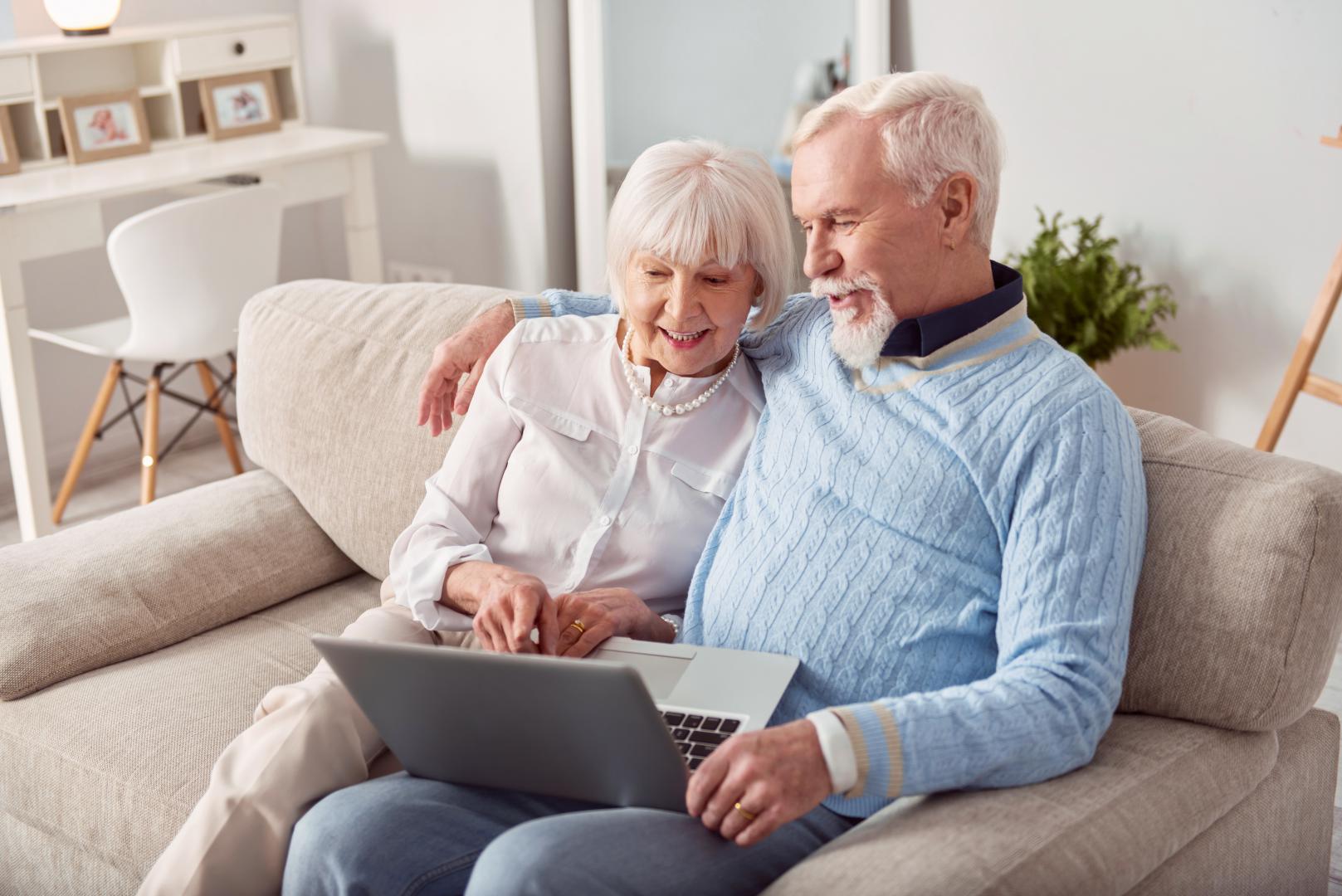 convenient-purchase-happy-elderly-couple-sitting-couch-living-room-choosing-new-laptop-online-store-together